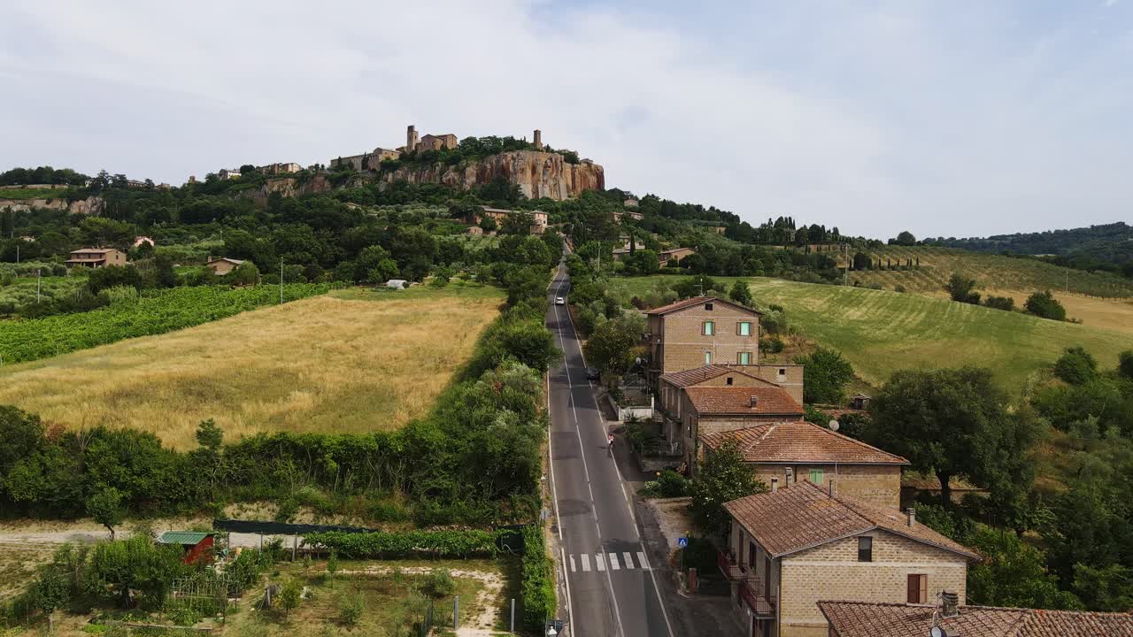 Peaceful road stretches toward ancient hilltop Orvieto, golden Tuscan fields