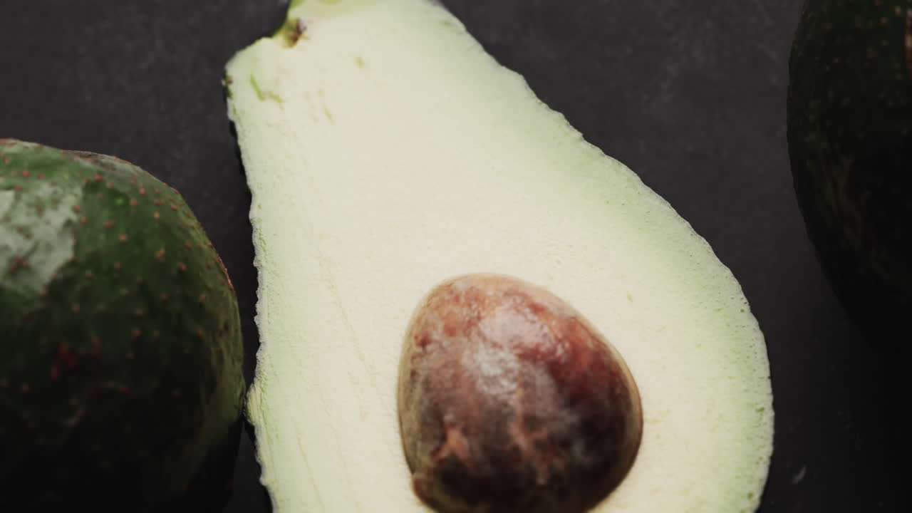 Micro video of close up of avocados with copy space on black background