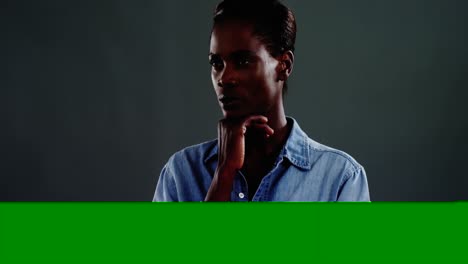 Androgynous-man-in-denim-shirt-posing-against-dark-background