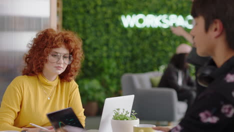 young business people brainstorming beautiful redhead woman using laptop computer sharing ideas showing friend ideas on screen enjoying teamwork in trendy office