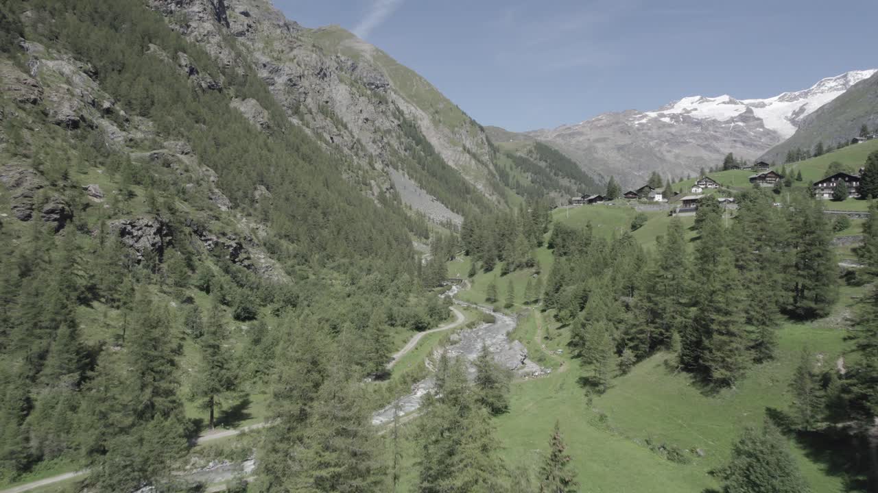 video con drones avanzando y ascendiendo sobre el río lys en un valle alpino con montañas nevadas en el horizonte