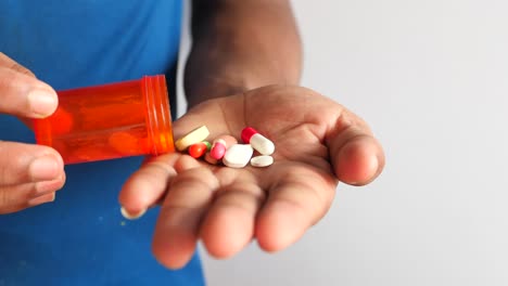 persona vertiendo pastillas del recipiente en la mano