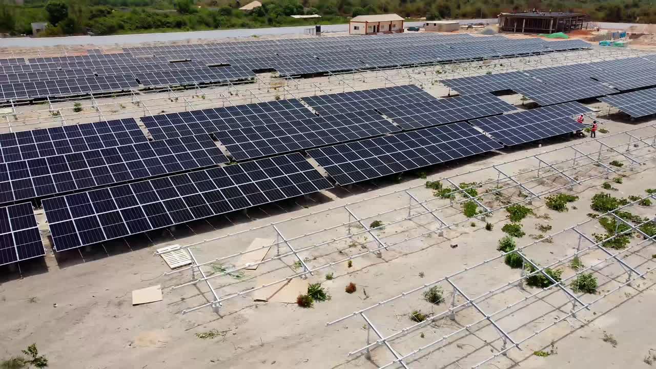 vista aérea de una granja solar con técnicos instalando paneles de módulos fotovoltaicos en áfrica subsahariana