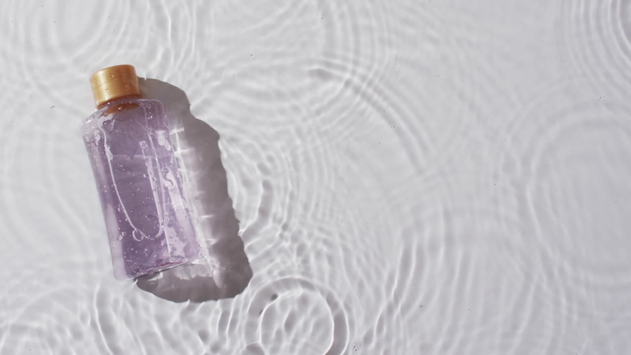 video de una botella de producto de belleza en agua con espacio de copia en fondo blanco