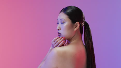 mujer asiática con cabello negro y maquillaje mirando a la cámara, copia espacio, cámara lenta