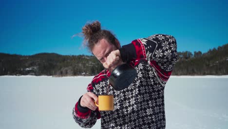 retrato de un hombre vertiendo café caliente a la taza de la tetera en el fondo de la naturaleza de invierno