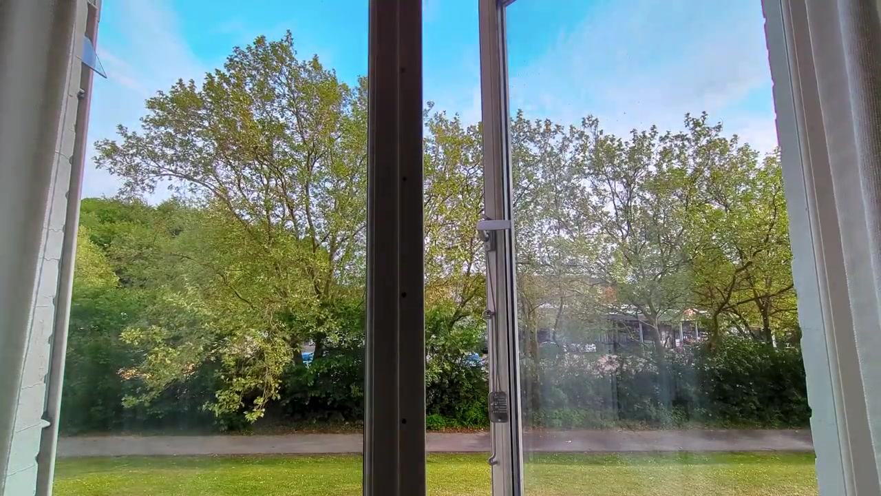 En højkvalitets 4K 30fps time-lapse filmet ud af et vindue i Hillerød, Danmark. Se vejret skifte, mens skyer hurtigt passerer over frodige grønne træer, en skjult parkeringsplads og et supermarked.