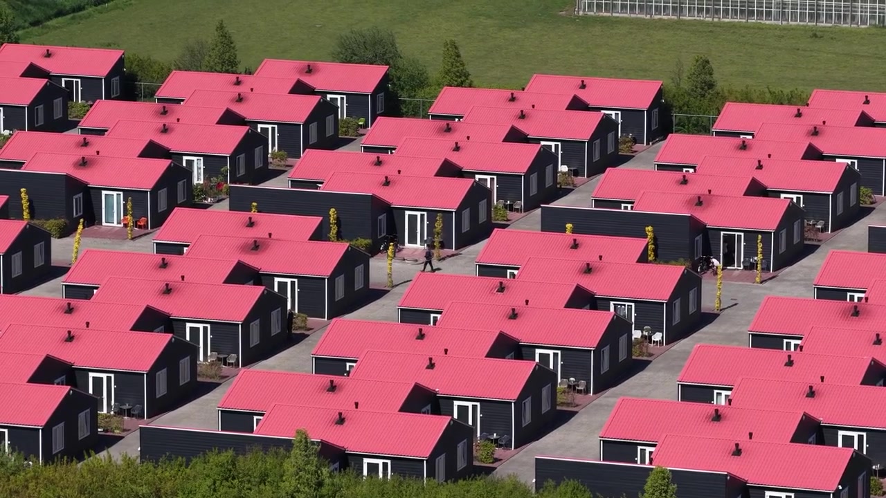 Dronekuva ilmasta turvapaikanhakijoiden vastaanottokeskuksesta Luttelgeestissä, Alankomaissa, näyttäen asuinrakennuksia ja maaseutuympäristöä