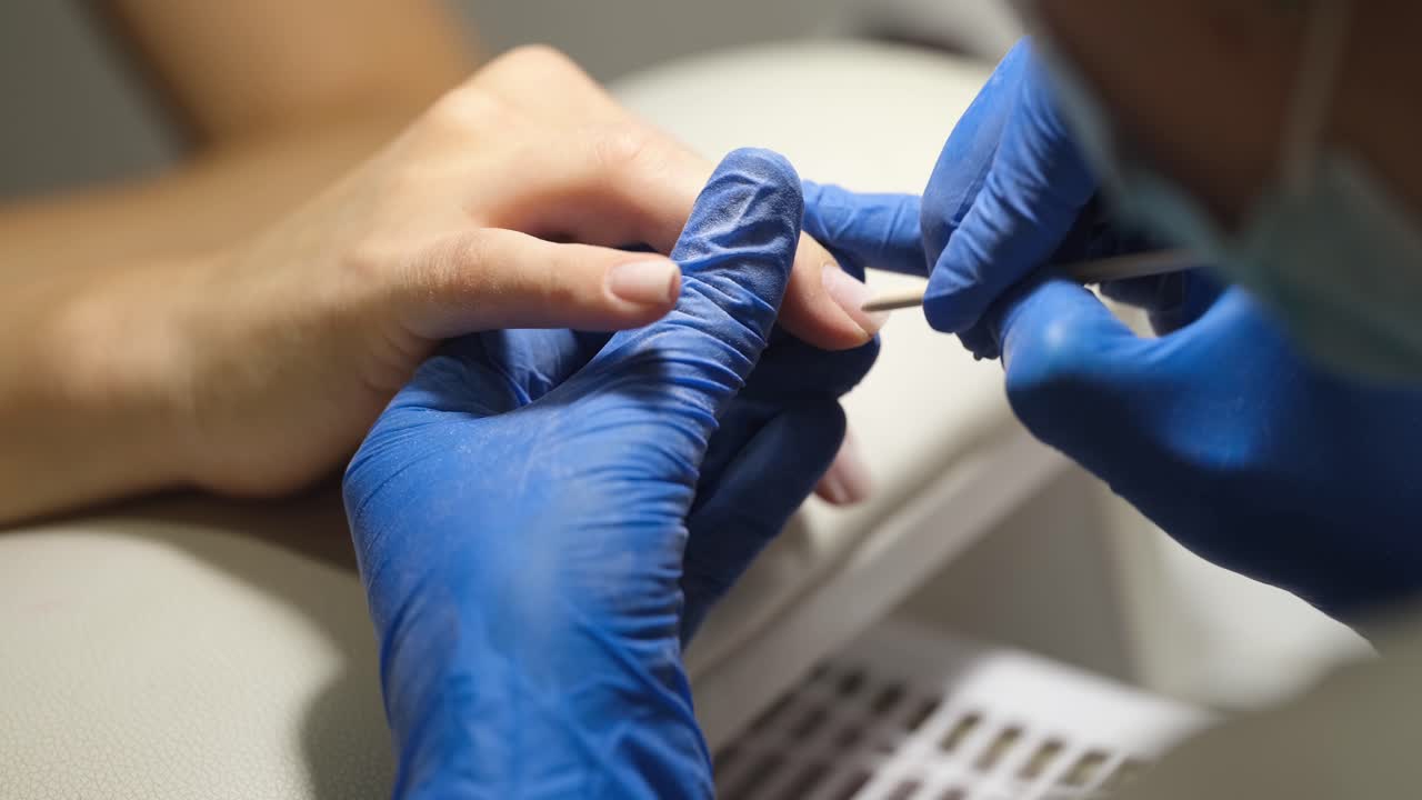 Manicurista realiza procedimiento de remoción de cutículas con palito de madera