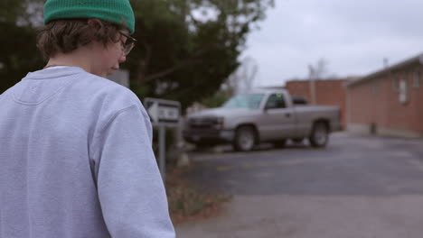 teenage boy with skateboard walks towards an alley in slow motion