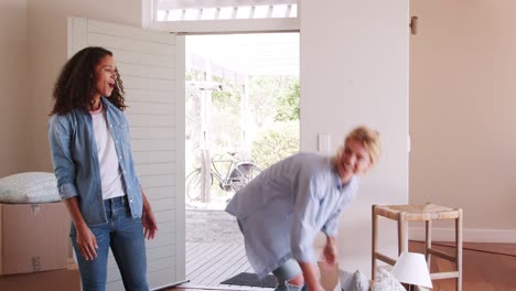 female friends carrying boxes into new home and celebrating on moving day