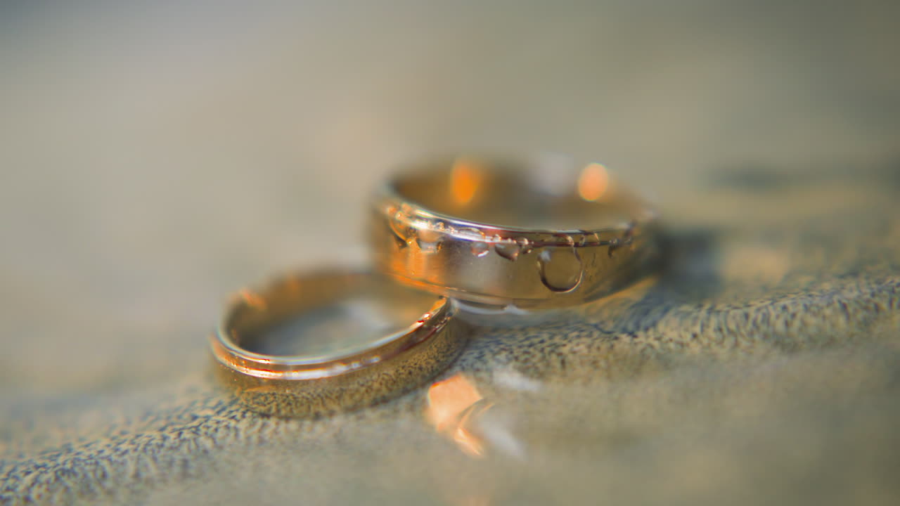 Elegant pair of gold wedding rings lies in clear water