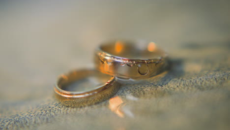 Elegant-pair-of-gold-wedding-rings-lies-in-clear-water