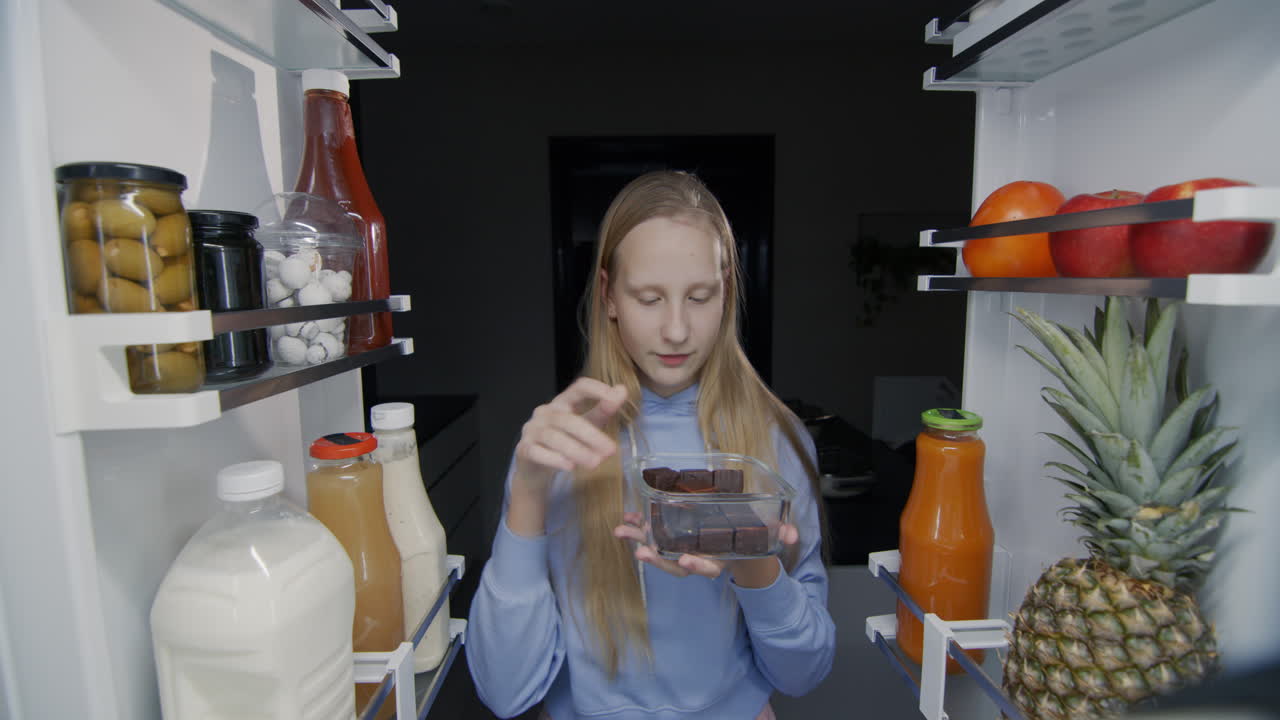 아이는 냉장고에서 과자를 먹습니다. 밤에 간식과 정크푸드를 먹습니다.