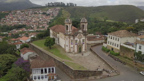 Spotlighting-the-stunning-architecture-of-São-Francisco-Church,-situated-in-the-heart-of-this-gold-rich-area,-surrounded-by-lush-green-forest-within-the-vibrant-commercial-hub-of-Ouro-Preto