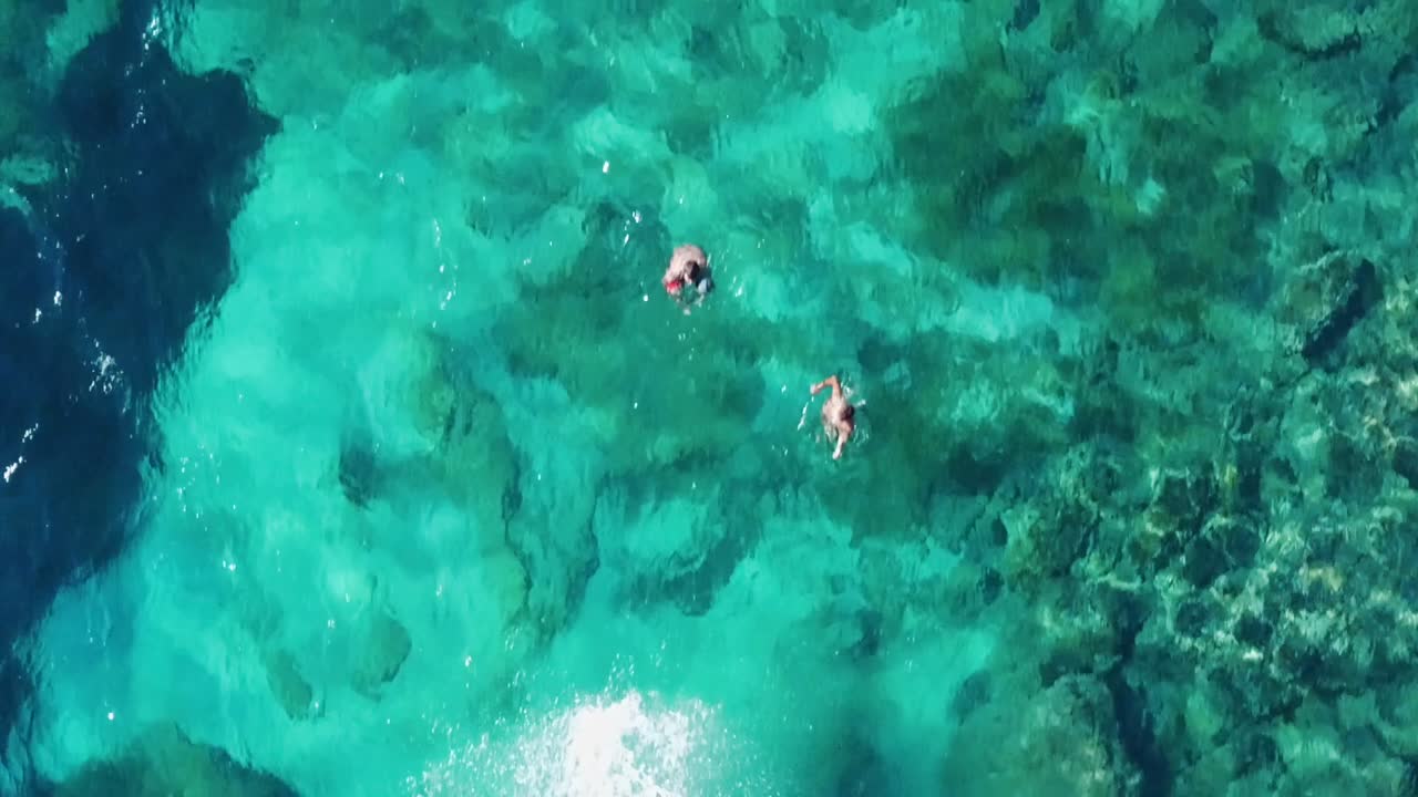 Cliff jump into turquoise clear blue water - Slow motion aerial top down footage