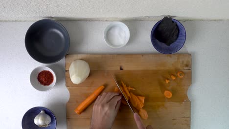 male hands cutting carrots into strips on wooden cutting board - top down view