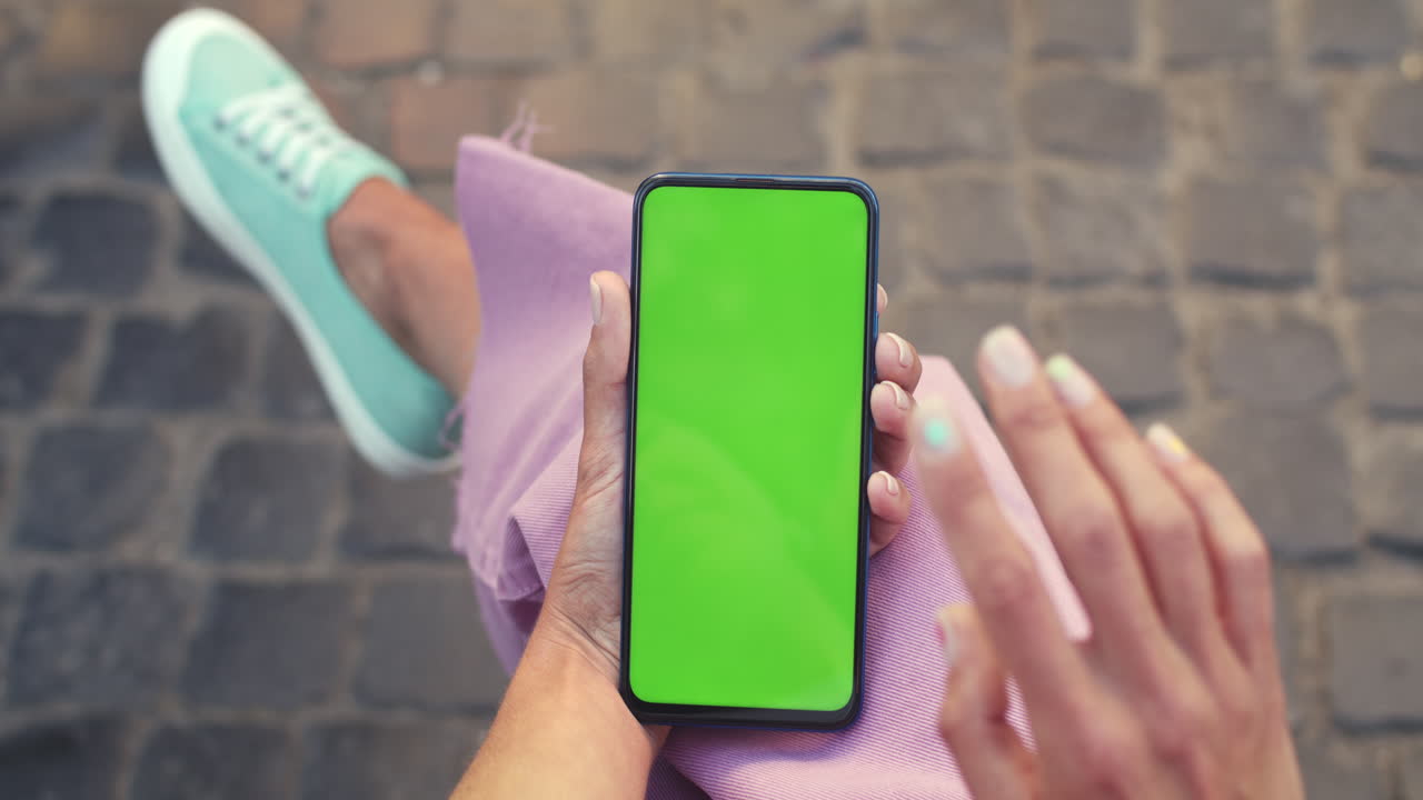 persona que sostiene un teléfono inteligente con pantalla verde al aire libre