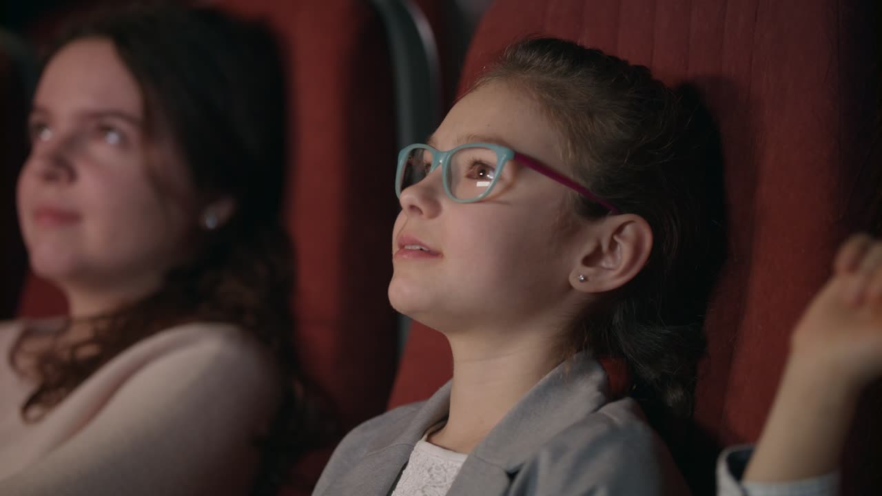 Jolie fille à lunettes regardant un film d'animation au cinéma. Enfant regardant un film