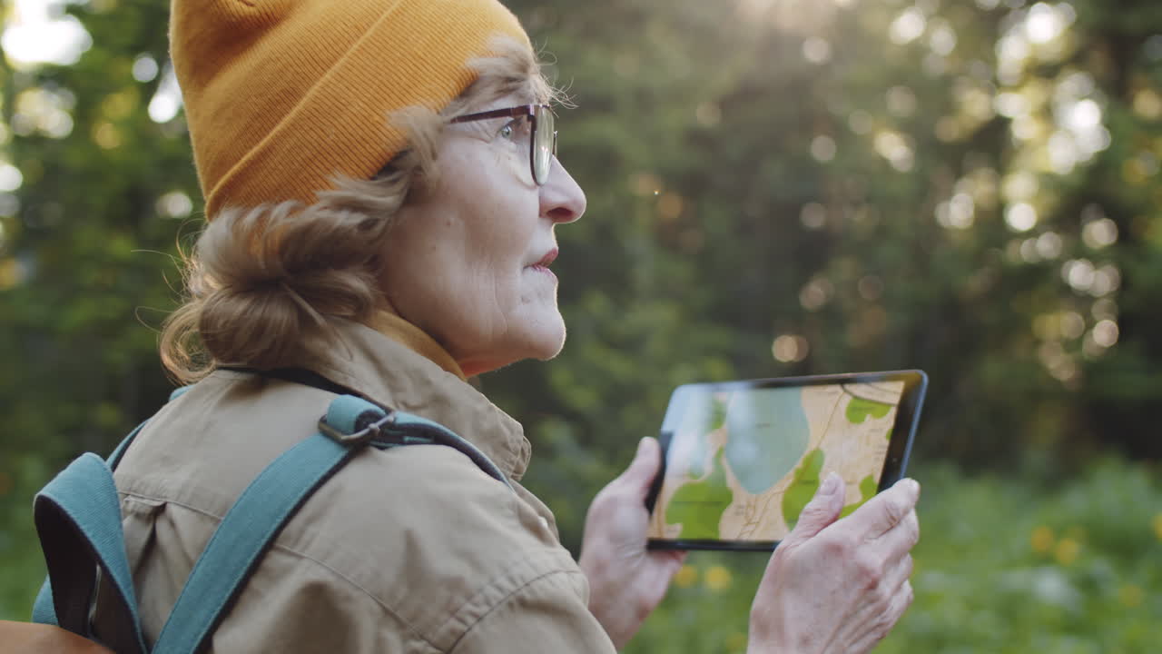 mujer anciana usando una tableta para navegar en el bosque