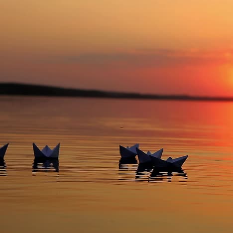 paper boats on a sunset lake
