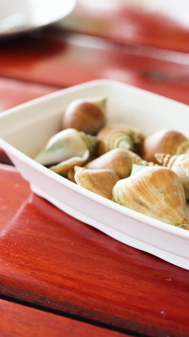 Mano che presenta un piatto di frutti di mare su un tavolo rosso