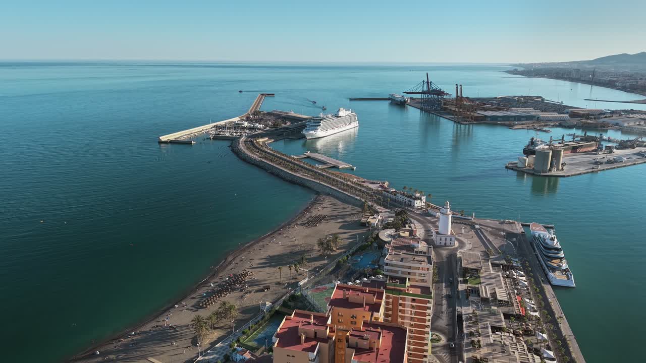 Port of Malaga showing cruise ships, lighthouse, beach, and clear blue Mediterranean waters - aerial