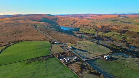 Drohnenaufnahmen-Aus-Der-Luft-Vom-Verkehr-Auf-Einer-Landstraße-Auf-Dem-Sadtworth-Moor-Mit-Goldenem-Landsee,-Stausee-Und-Weitem-Blick-Auf-Die-Pennine-Hügel