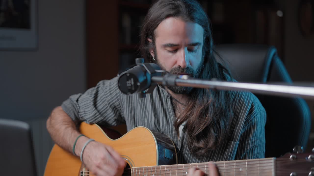 hombre tocando la guitarra acústica en el estudio casero