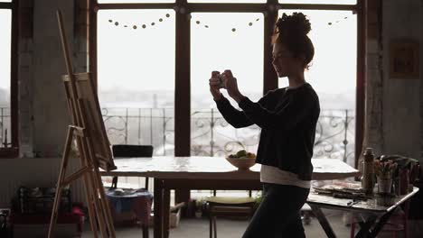 girl taking picture of the painting she drew on her smartphone.