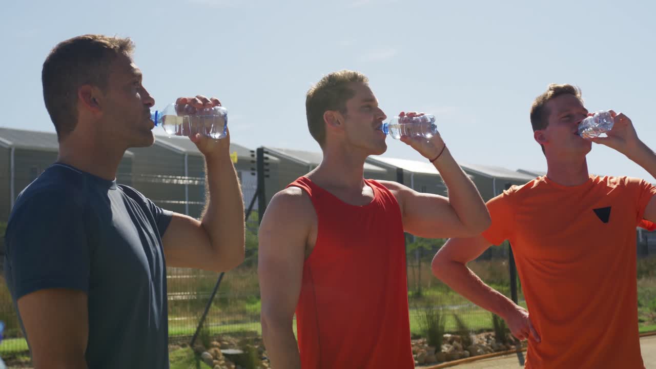 hombres bebiendo agua después del entrenamiento en un día soleado