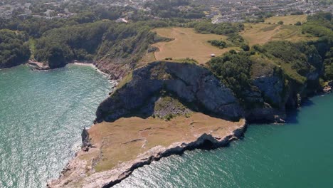 vuelo aéreo sobre el famoso mirador de la larga cantera rodeado por el océano atlántico y la ciudad de torquay al fondo