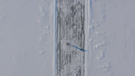 Drone-aerial-footage,-overhead-of-an-ice-skater-on-a-frozen-lake