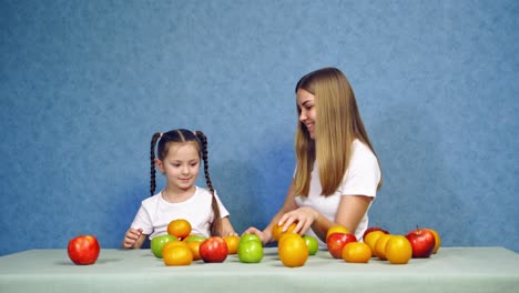 girls with fruit on table. beautiful woman and small girl with healthy food