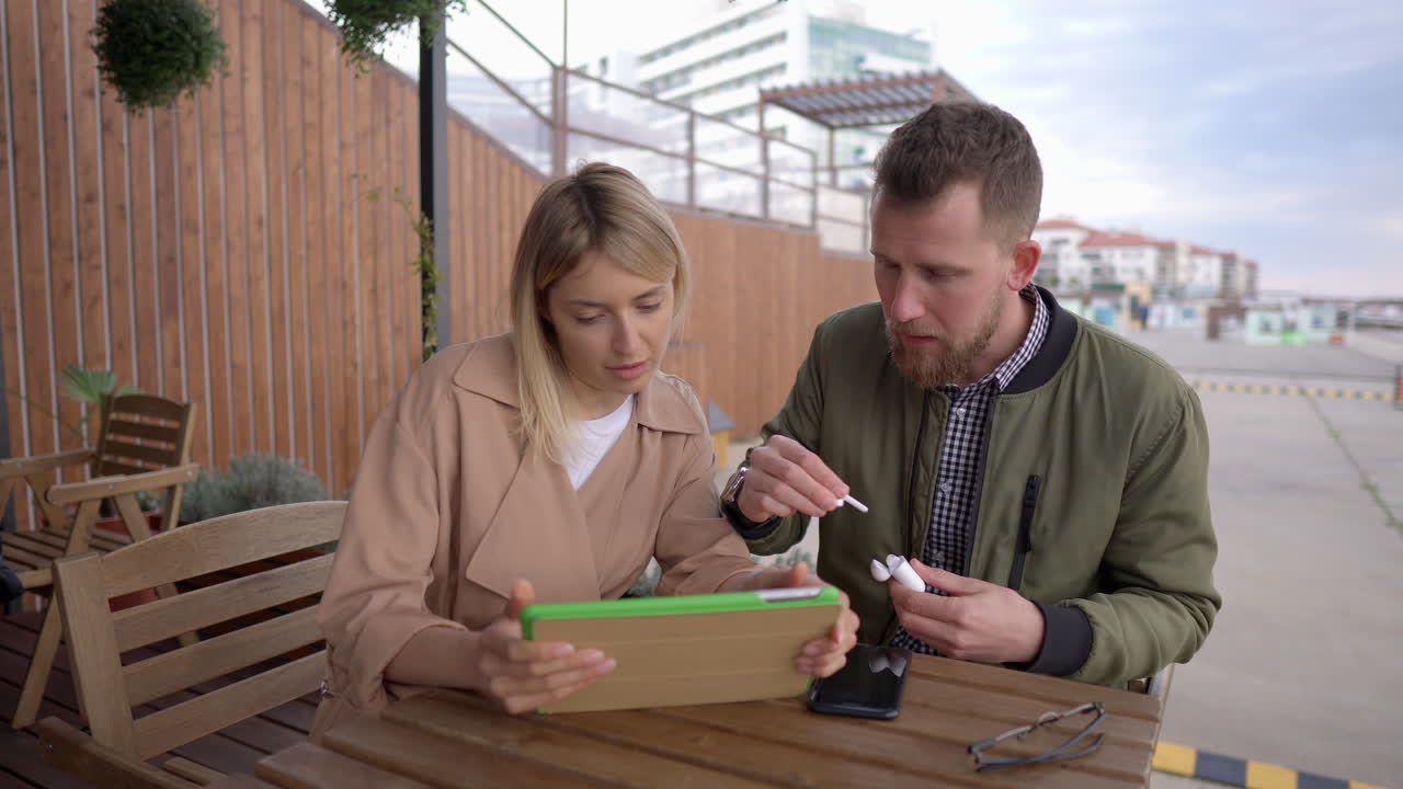 pareja discutiendo en la tableta en un café al aire libre