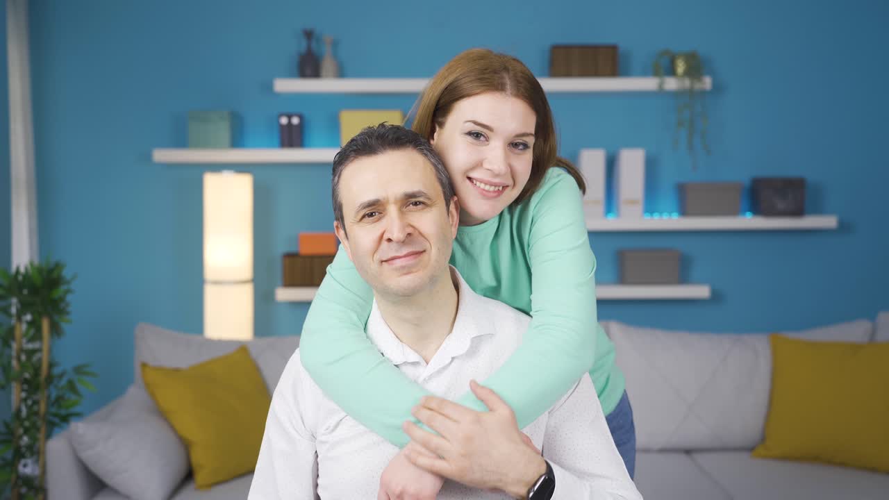 Giovane ragazza adulta abbraccia suo padre. Guardano insieme l'obiettivo.