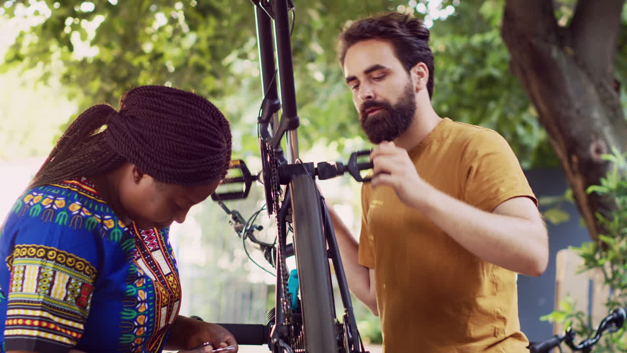 um casal multirracial examina uma bicicleta danificada