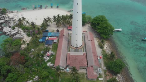 White-lighthouse-at-Lengkuas-Island-tropical-blue-water,-aerial