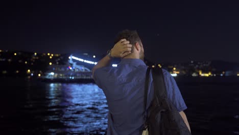 un joven exitoso mirando el mar nocturno y riendo.