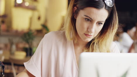 mujer joven atractiva trabajando en una computadora portátil en un café