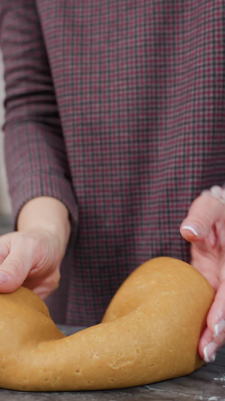 왼손에 팔를 은 여성은 주방 카운터에서 신선한 반죽을 고, 집에서 만든 김을 준비합니다. 현대 주방 설정에는 롤링 핀, 빨간 불, 색 캐비 및 따뜻한 조명이 있습니다.