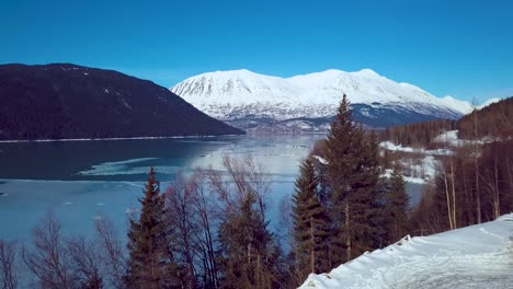 4k drone video of snow covered lakeside mountains in alaska during winter