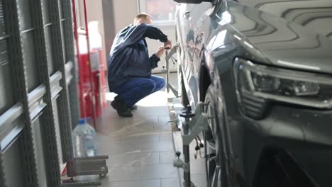 mechanic performing a wheel alignment process in a modern workshop. professional equipment is used to ensure accurate vehicle alignment for optimal performance and safety