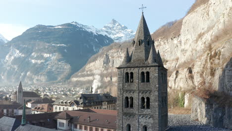 Low-angle-aerial-om-imposing-old-church-tower-of-the-Saint-Maurice-Abbey-in-an-idyllic-town