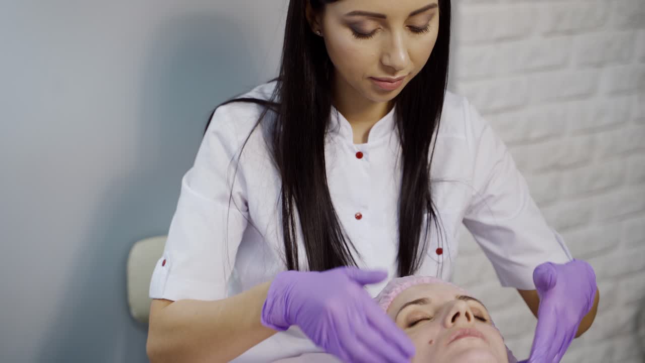 Ung kvinde nyder ansigtsmassage på en spa-salon. Skønhedsbehandling.