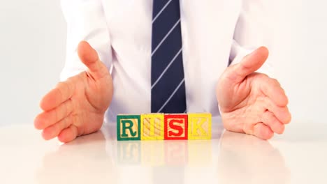 businessman showing the word risk with alphabet block