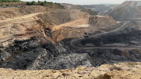 large mining dump trucks spraying water on the road that goes inside the coal mine in india
