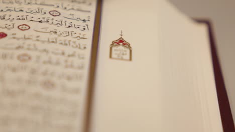Moving shot of an open Quran lying on a table, the shot is moving from right to the left side