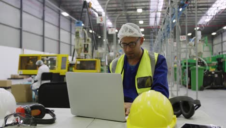 warehouse worker using laptop in factory