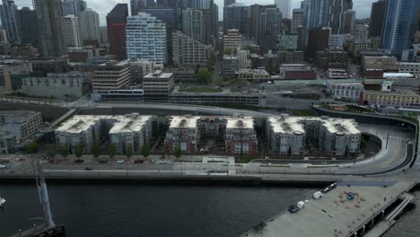 overhead drone shot of coastal residential condominium buildings along seattle waterfront pier with downtown background - seattle, washington, usa